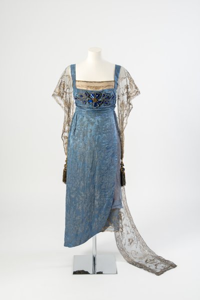 Blue Figured Silk Evening Dress with Gold Net Sleeves and Train Embroidered in Gold Metal Strip and Decorated with Blue Gems and Tassels, 1911 by Lucy Christiana, Lady Duff Gordon